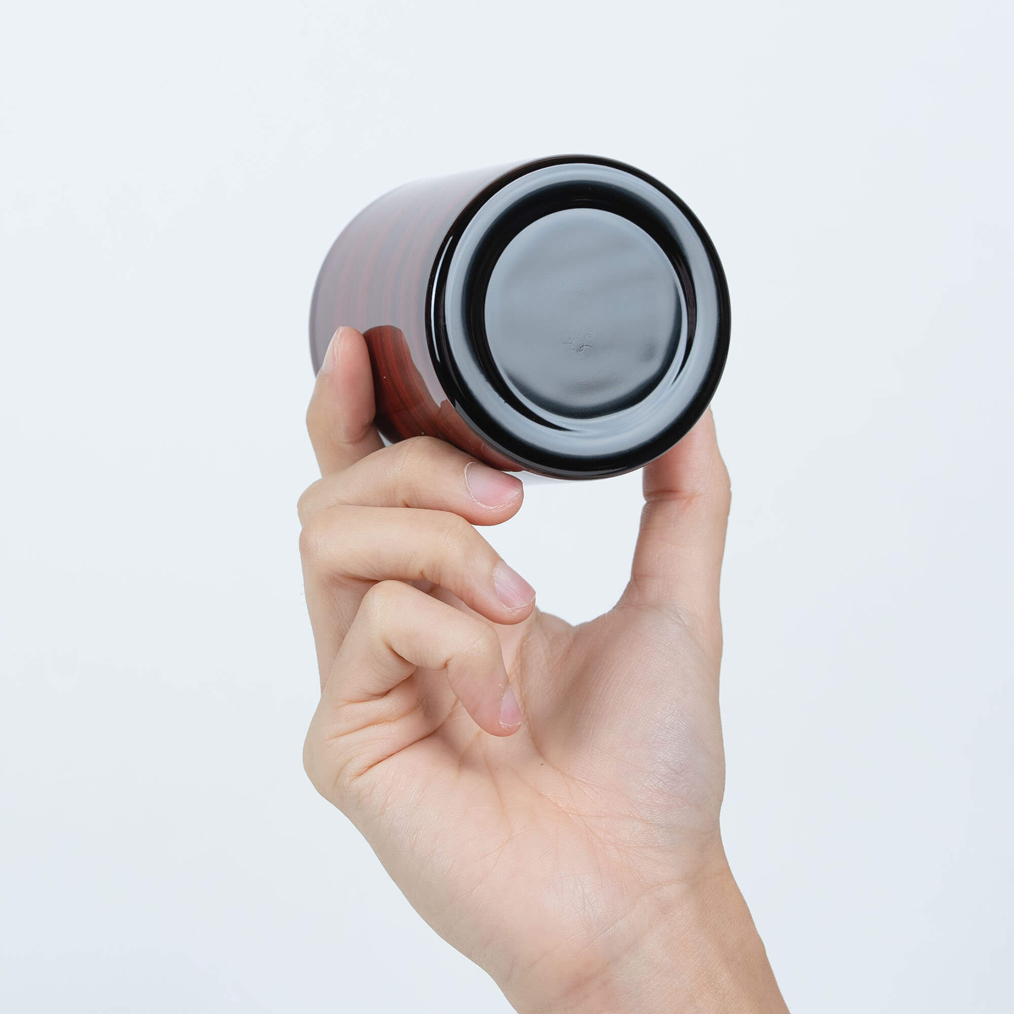 Base view of a red Japanese lacquered stainless steel sake cup held in one hand