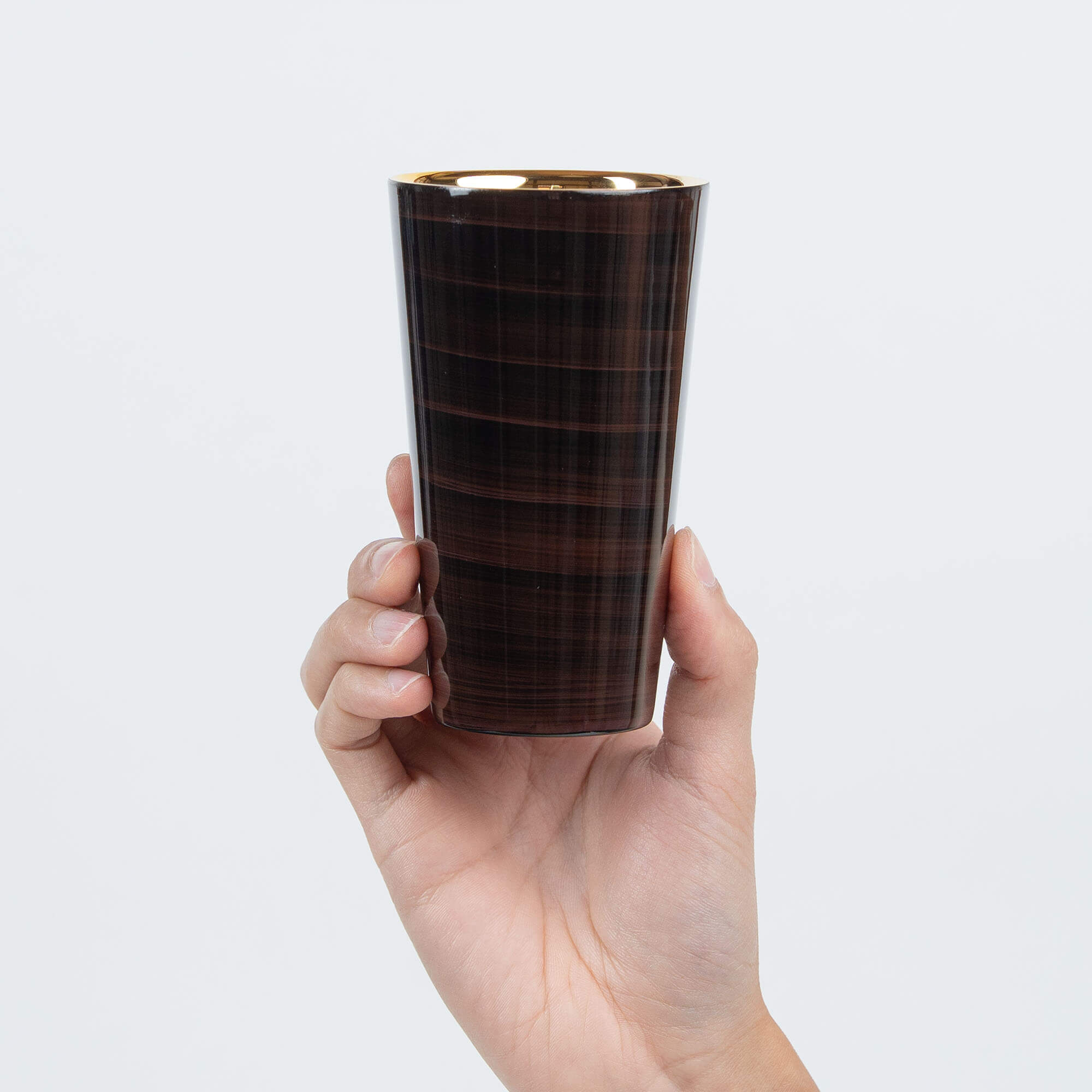 Hand holding a brown Japanese lacquered 300ml stainless steel tumbler upright