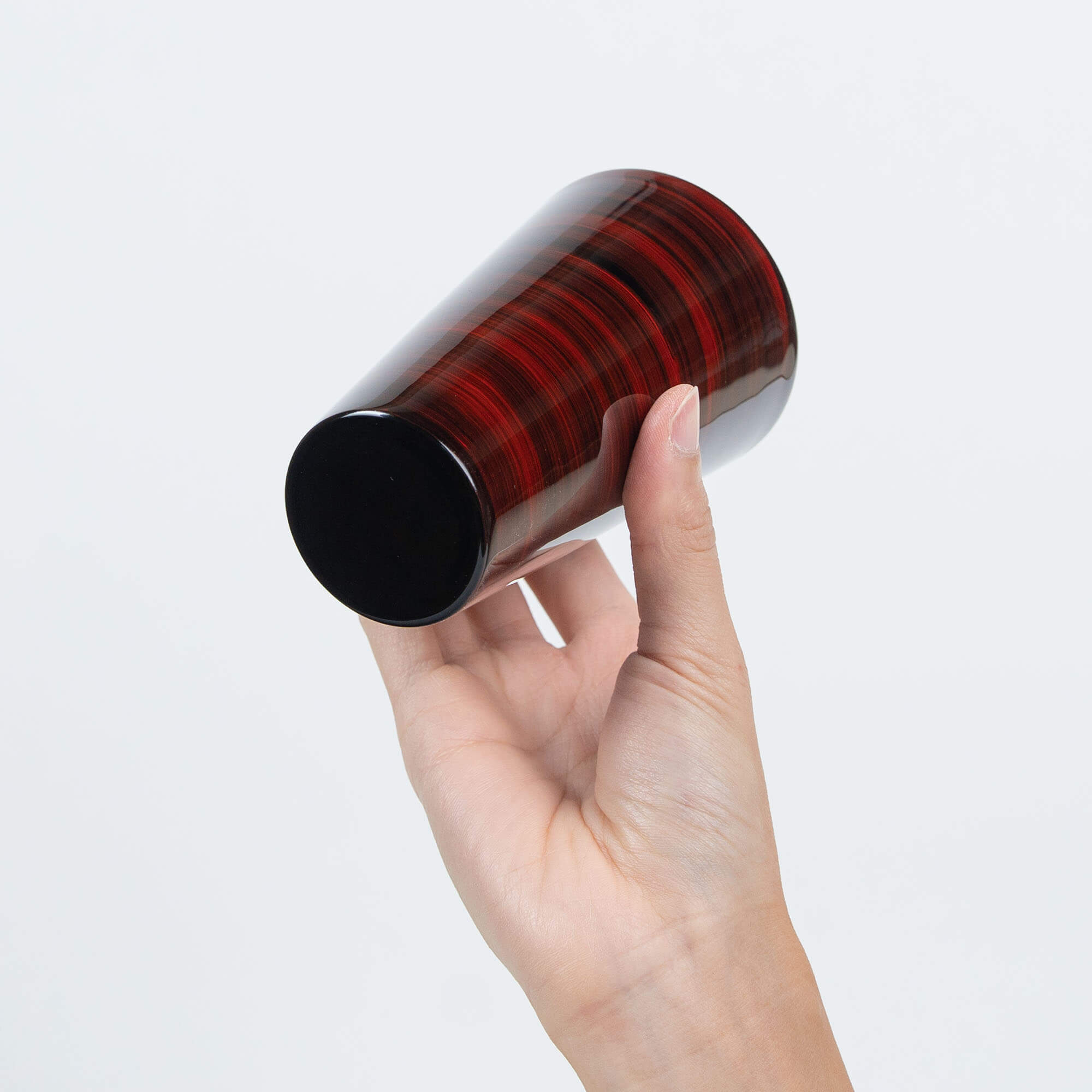 Base view of a red Japanese lacquered stainless steel tumbler held in one hand