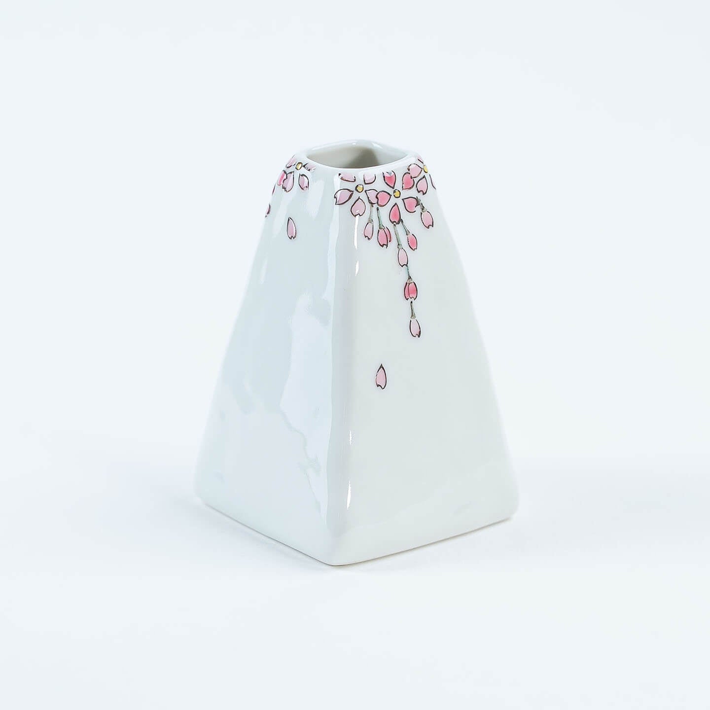 A white Kutani-yaki ceramic vase in the shape of Mt. Fuji with a pink cherry blossom pattern.
