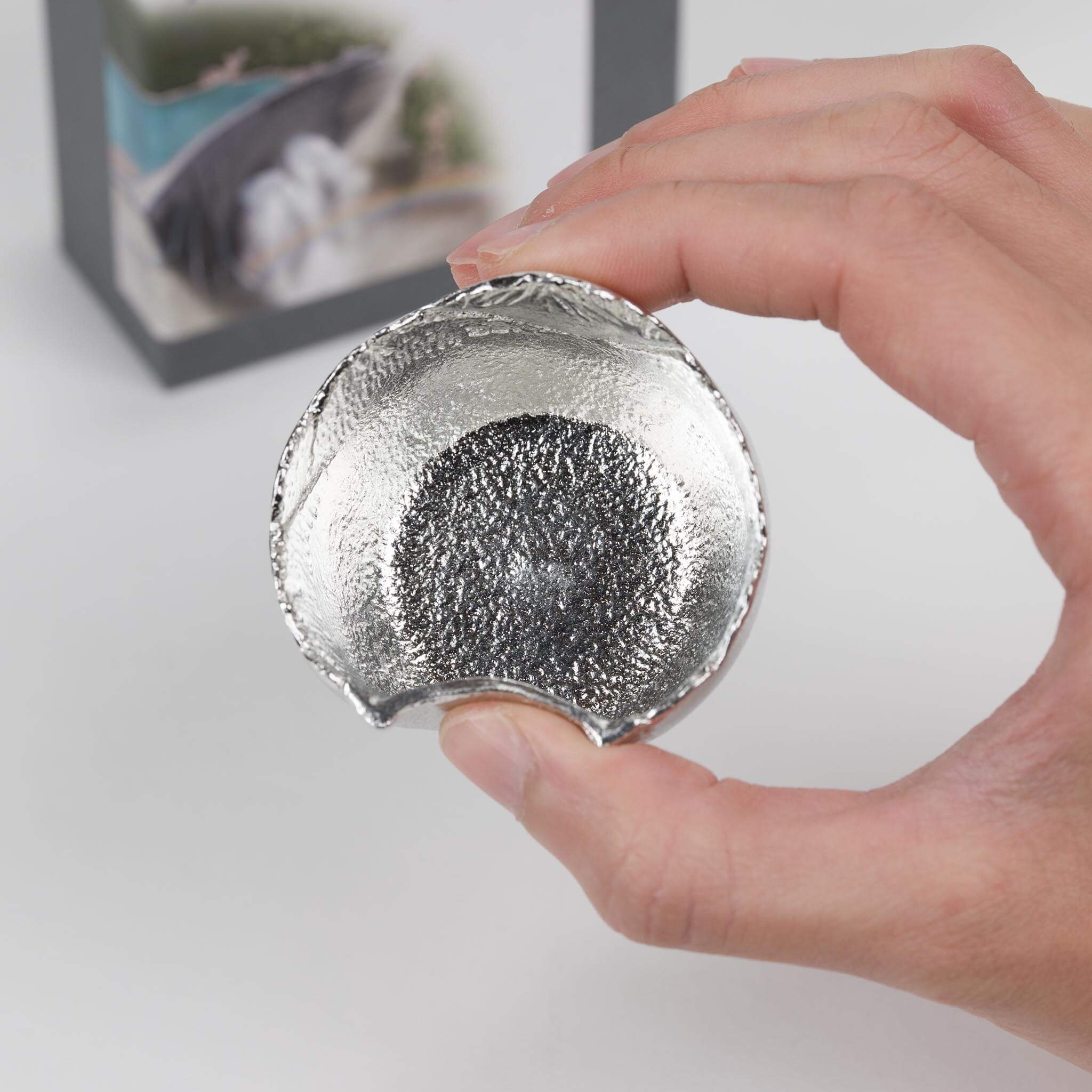 Demonstrating how to cover the hole of the Nousaku tin cup while enjoying Japanese sake.