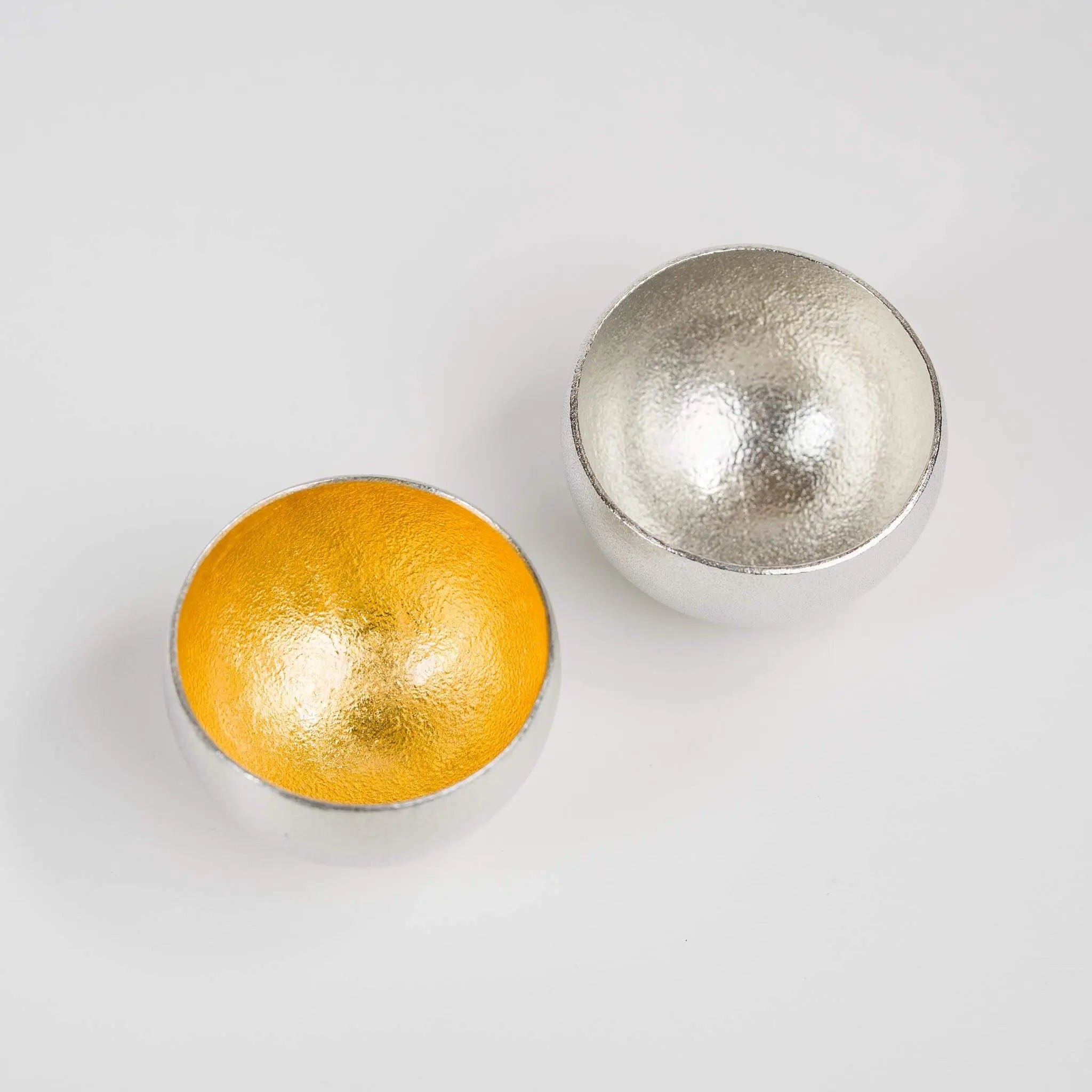 Close-up shot of the rounded base design and the contrasting interior textures of the tin and gold cups.