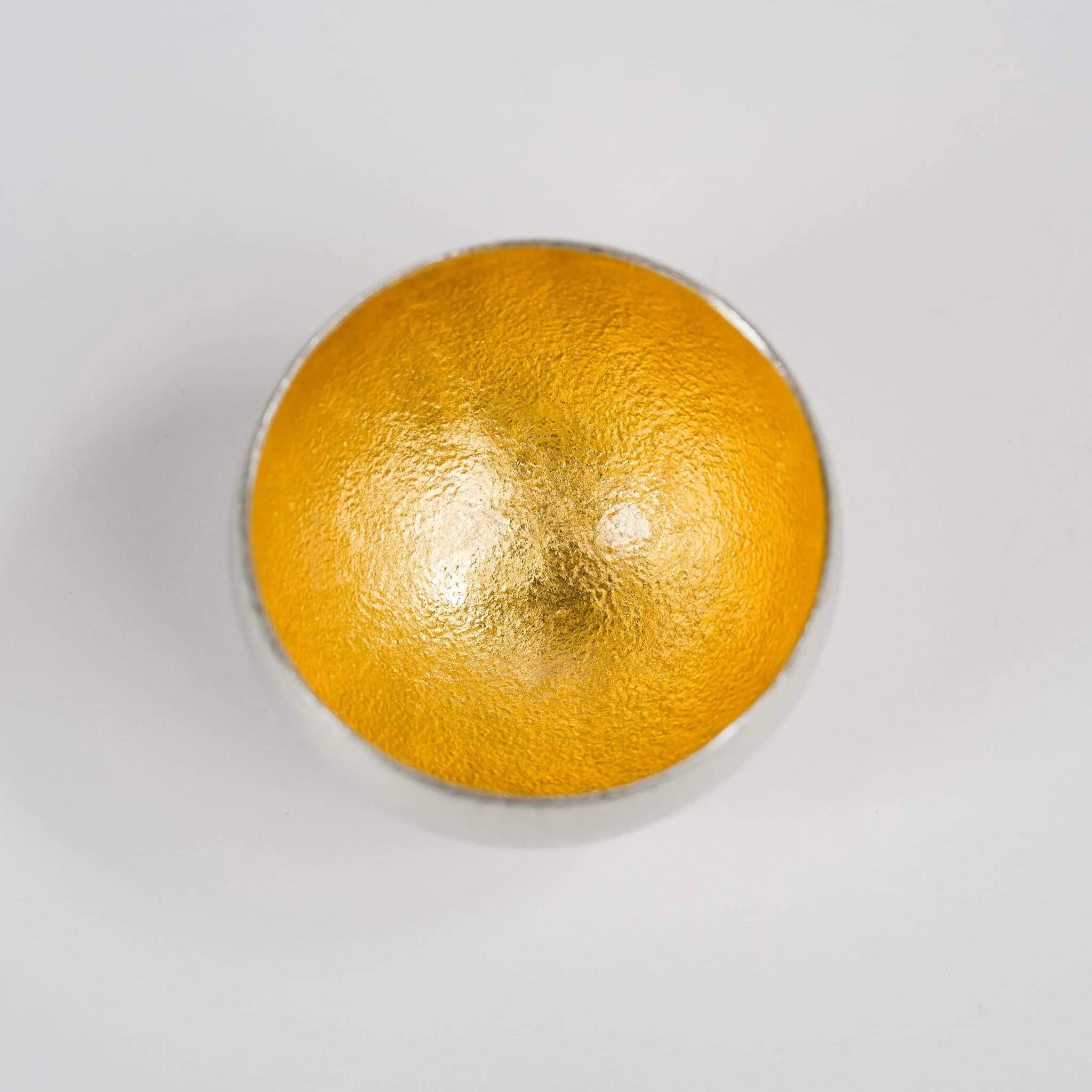 Top-down view into the radiant gold leaf lined interior of the rocking sake vessel.