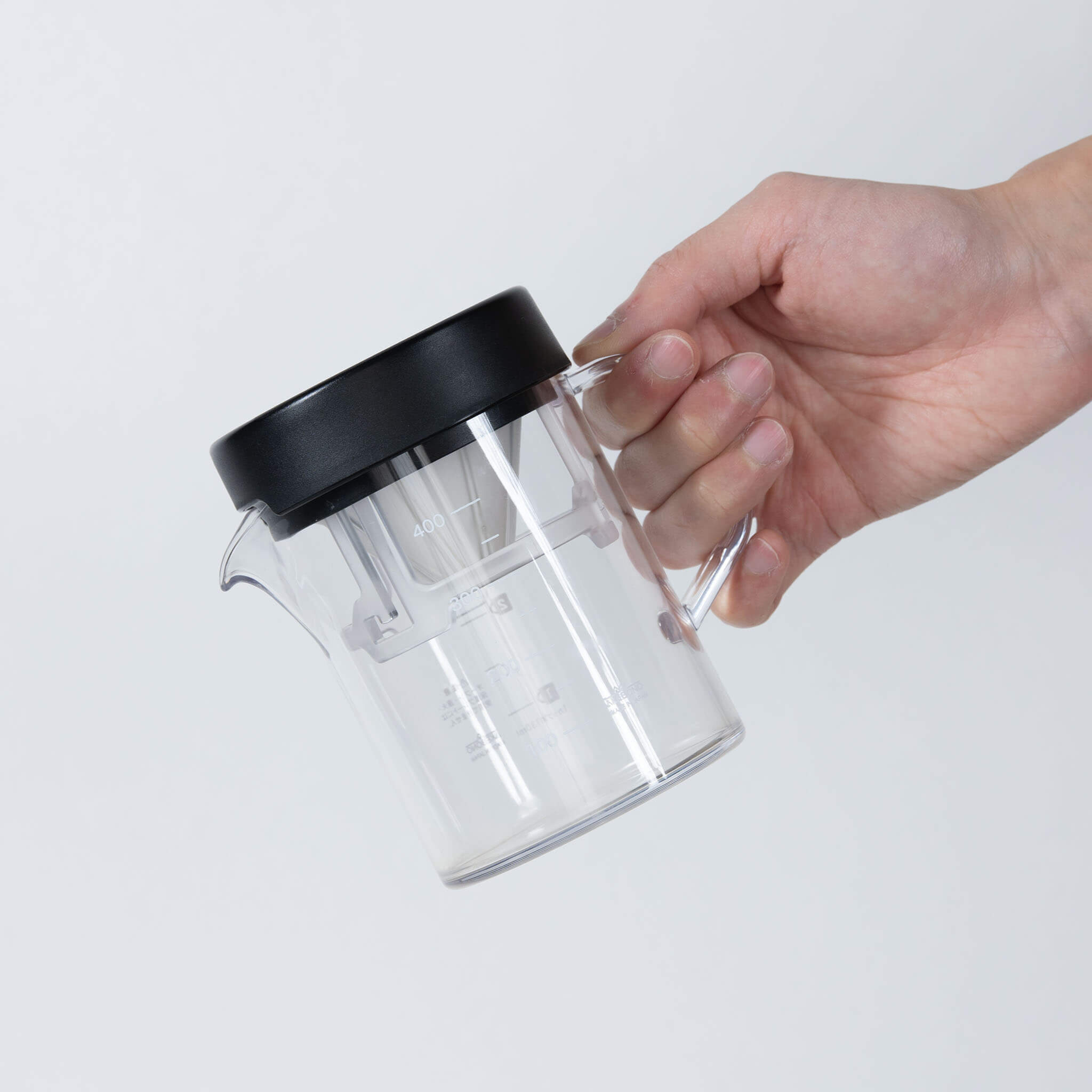 Hand holding STRON Compact Dripper Set in compact storage configuration, tilted view 