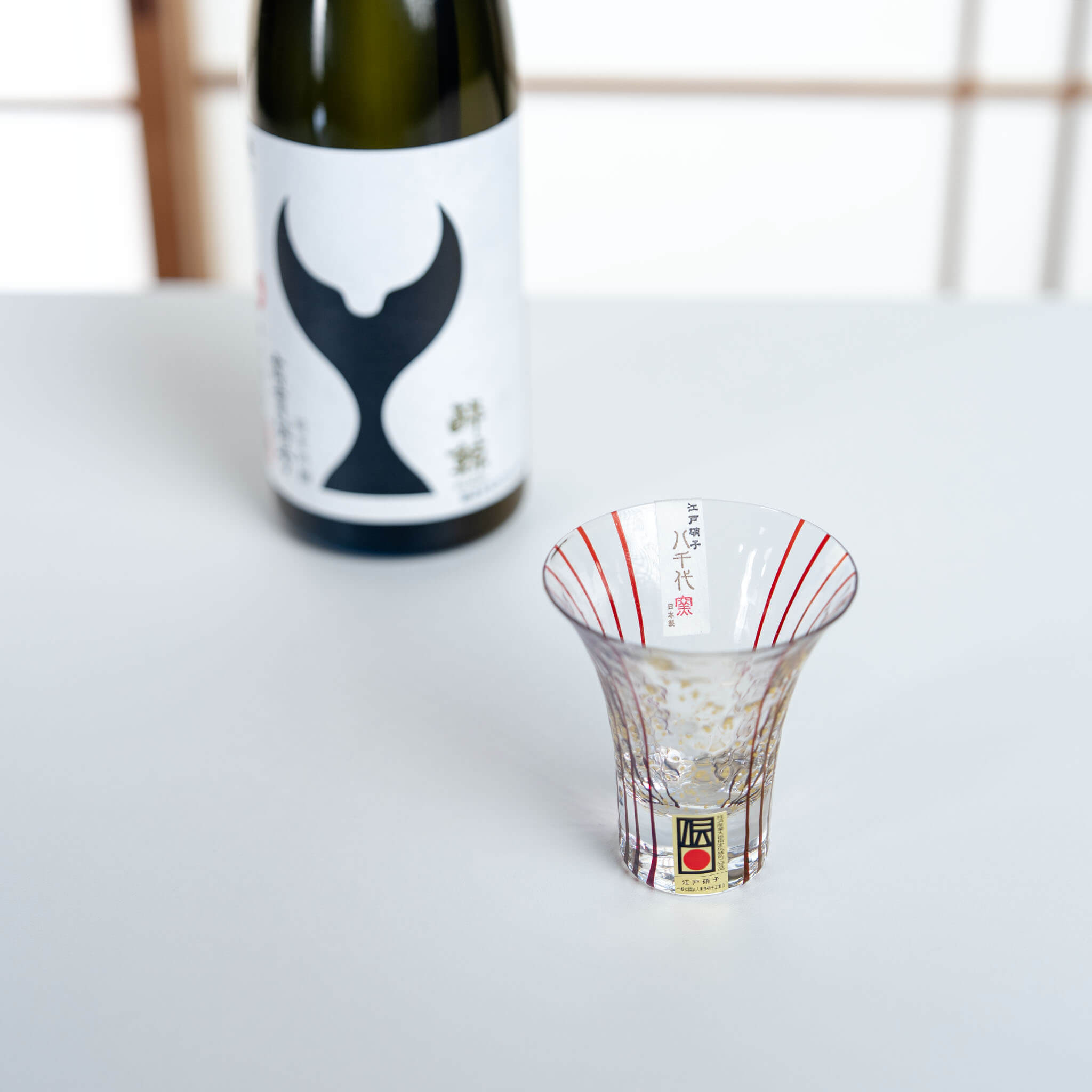 Hanamizake handmade sake glass displayed beside a Japanese sake bottle