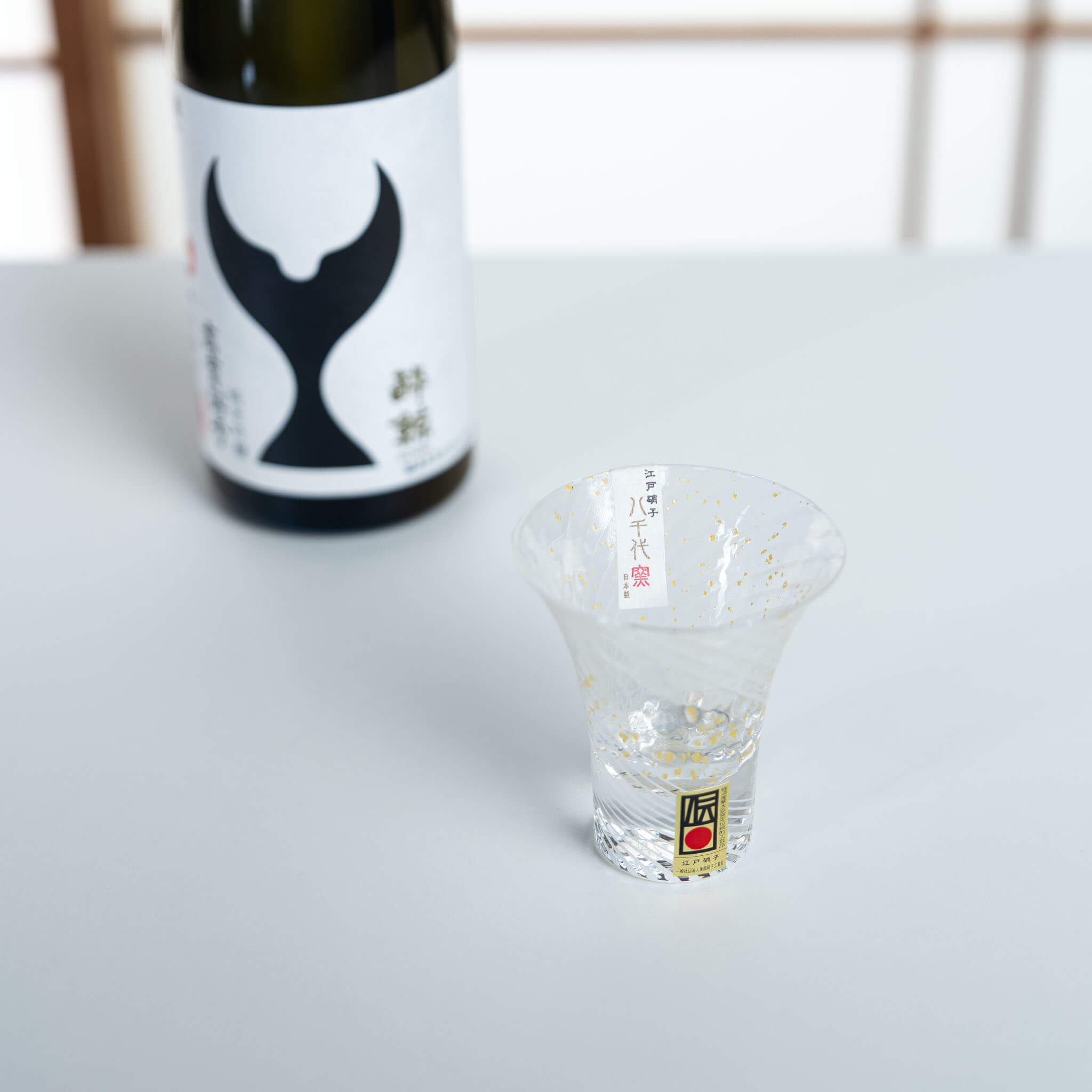 Yukimizake handmade sake glass displayed beside a Japanese sake bottle