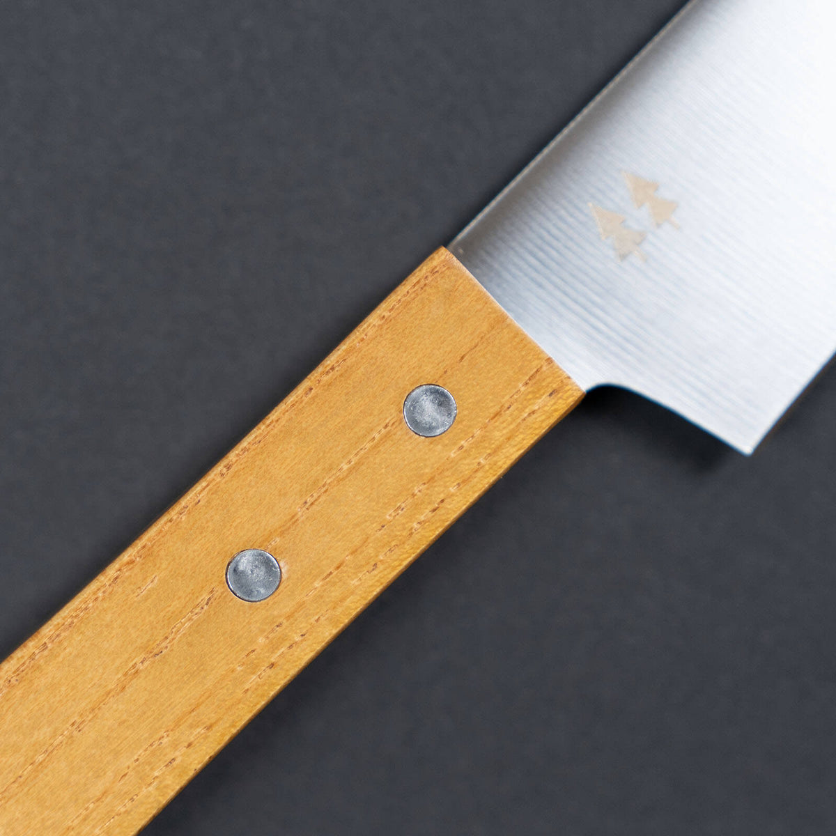 Close-up of the keyaki wood grain and two metal rivets on the Shizuhamono Morinoki utility knife handle